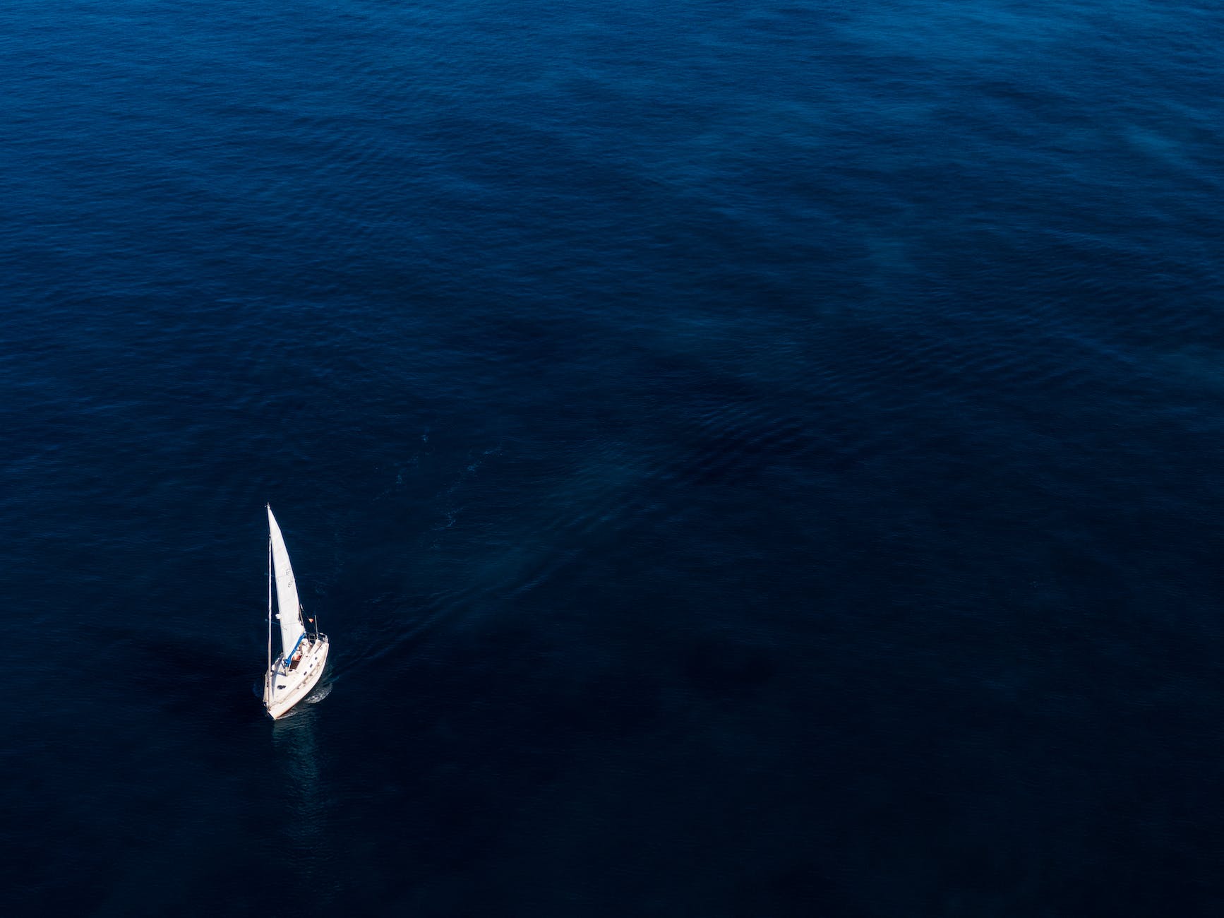 A sailing boat navigating in the deep blue sea